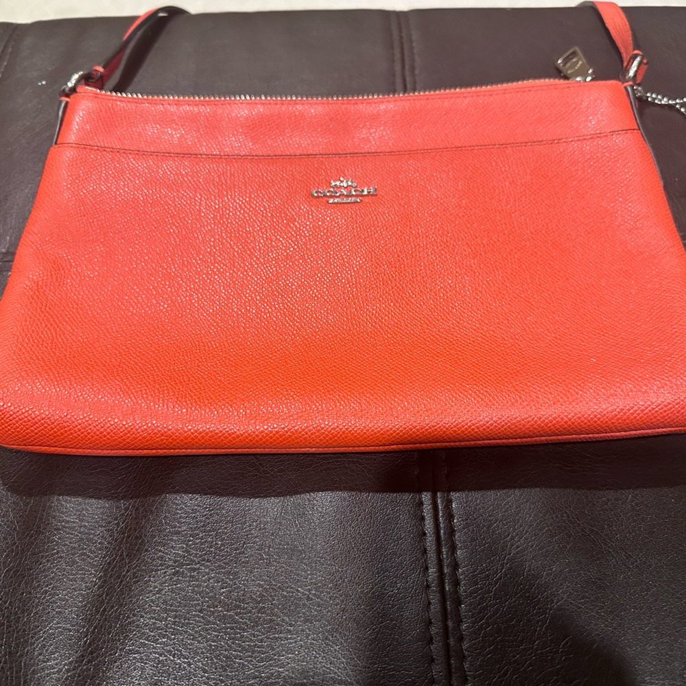 Authentic orange crossbody purse by Coach.